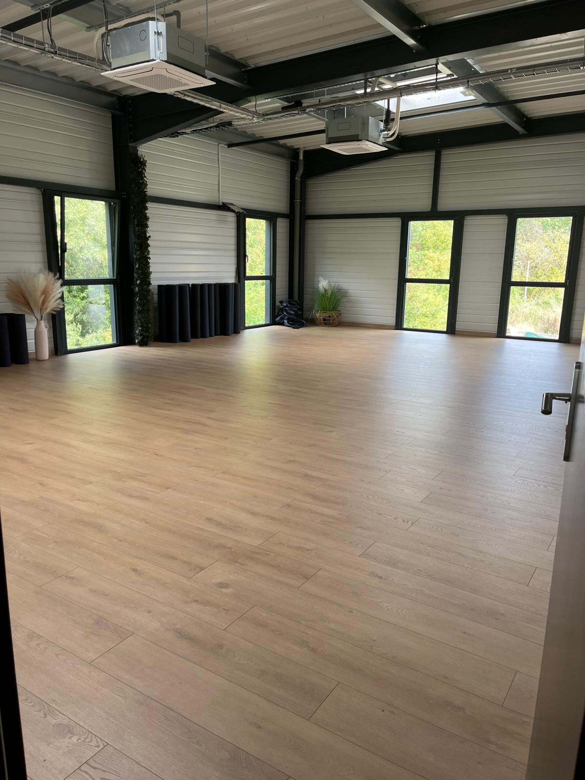 Studio lumineux de Session Sport avec parquet et espace libre pour les cours doux.